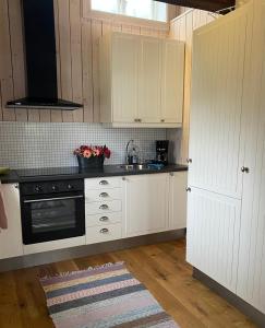 雪平斯维克Bo i egen stuga på härlig ölandsgård的厨房配有白色橱柜和黑炉。