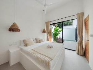 爱妮岛Bahala Na Villas的白色的卧室设有一张大床和一个窗户