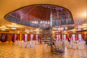 维什戈罗德维什戈罗德城堡酒店的一个带白色桌子和螺旋楼梯的大型宴会厅