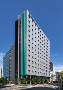 福冈Prince Smart Inn Hakata的一座高大的白色建筑,上面有一条绿条