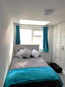 WembleyStadium Nook的一间卧室配有一张带蓝色窗帘的床和一扇窗户