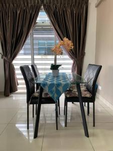 努沙再也Hud hud Homestay Gelang Patah的一张带椅子的玻璃桌和一个花瓶