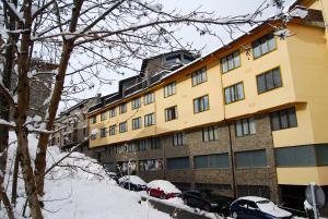 恩坎普德尔梅尔加公寓的一座大型黄色建筑,汽车停在雪中