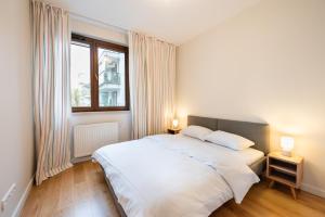 华沙Sokratesa Estate Ideal Apartment的卧室配有白色的床和窗户。