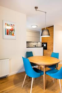 华沙Sokratesa Estate Ideal Apartment的厨房以及带木桌和蓝色椅子的用餐室。