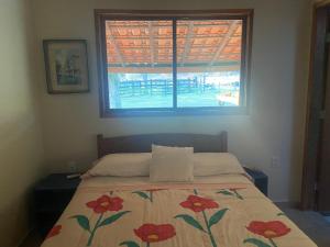 博尼图Fazenda a 15 min do centro com Rio Particular的一间卧室配有一张带鲜花毯子的床和窗户。