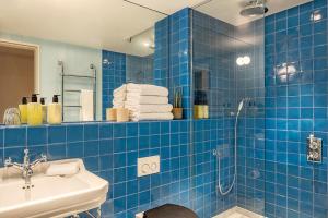 马盖特Fort Road Hotel的蓝色瓷砖浴室配有淋浴和盥洗盆
