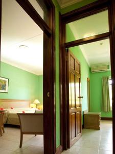 拉迪格岛格雷瓜尔公寓的一间设有绿色墙壁的客房和一间配有床铺的卧室