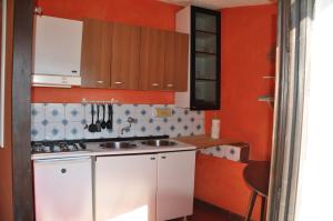 马西亚娜马里纳Cotetonda - Appartamento Taccola的一间小厨房,配有橙色的墙壁和白色的橱柜