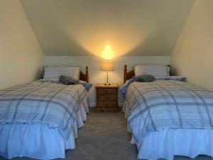 斯托诺韦Sighthill Cottage, North Tolsta的一间卧室配有两张床和床头灯。