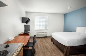格尔夫波特Extended Stay America Select Suites - Gulfport的酒店客房配有一张床和一张带炉灶的书桌