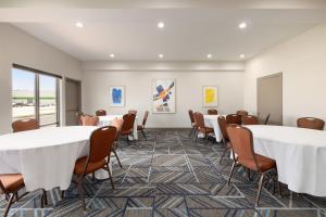 奥珀卢萨斯Holiday Inn Express & Suites Opelousas, an IHG Hotel的一间会议室,配有桌椅和绘画作品