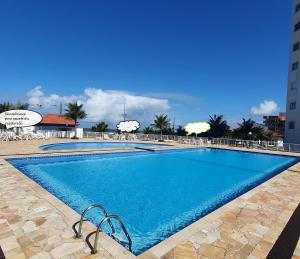 马蒂尼奥斯Apto Resort Cambuhy frente Mar até 6 pessoas的一座带椅子的大型蓝色游泳池和一座建筑