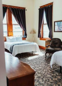 利德市政厅酒店的一间卧室设有两张床、一把椅子和窗户。