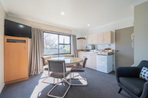 蒂阿瑙Te Anau Motel & Apartments的一间带桌椅的客厅和一间厨房