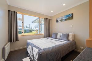 蒂阿瑙Te Anau Motel & Apartments的一间卧室设有一张床和一个大窗户