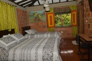 蒙特内哥罗Finca Hotel Villa Mariana的一间卧室设有两张床、一张桌子和窗户。