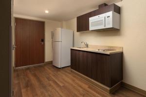 梅里达Extended Suites Merida Siglo XXI的厨房配有白色冰箱和木制橱柜。
