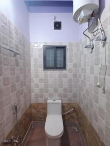 阿加尔塔拉Ujjayanta Homestay的一间带白色卫生间的浴室和窗户。