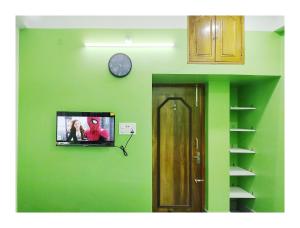 阿加尔塔拉Ujjayanta Homestay的一面绿色的墙,上面有时钟和一台电视
