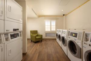 克雷塔罗Extended Suites Queretaro Juriquilla的洗衣房配有洗衣机和绿色椅子