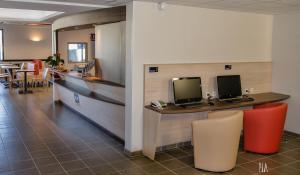 安锡阿纳西王牌酒店的大堂设有2个显示器和椅子的柜台