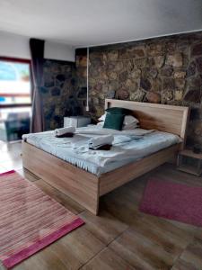SviniţaCasa David的一间卧室配有一张木床和石墙