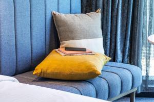 墨尔本voco Melbourne Central的蓝色沙发上枕头上的遥控器