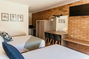 布莱克尔Oasis Motor Inn Blackall的酒店客房设有两张床、一张书桌和电视