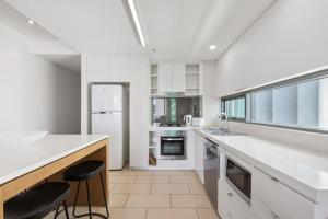 布里斯班Quattro Apartments的一间带白色柜台和大窗户的厨房
