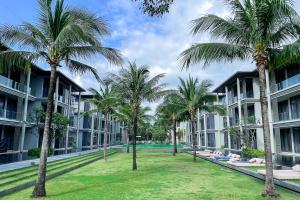 迈考海滩Baan Mai Khao - 2 Bedroom Luxury Condo- Direct Pool & Beach Access的一座楼前种有棕榈树的庭院