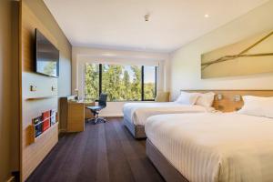 堪培拉堪培拉皇冠假日酒店的一张桌子和一扇窗户,配有两张床铺。