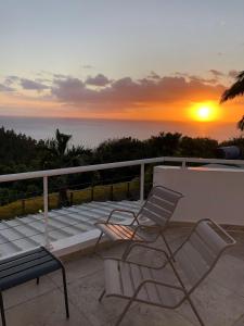 珀蒂蒂勒Villa spa Grand Anse的阳台上的长凳和两把椅子享有日落美景