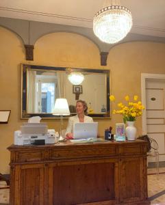 蒙特瓦尔基Palazzo Mari suite & rooms b&b的坐在一张桌子上的手提电脑的女人