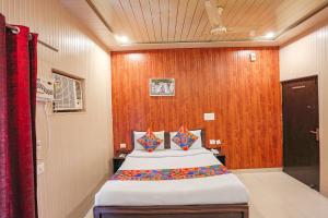 德拉敦FabExpress Limewood的一间卧室设有一张带木墙的大床