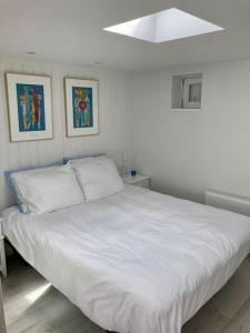 海滨诺德韦克Beachhouse Stranddistel 100m from the beach的卧室内的一张白色床,墙上挂着两张照片