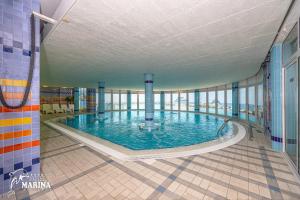 塞尔瑟马里纳酒店的一座大型游泳池,位于一座带窗户的建筑内