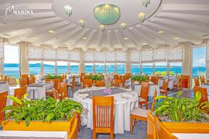 塞尔瑟马里纳酒店的餐厅设有桌椅,背景为大海