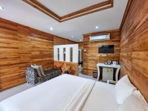 奥南海滩Phuvara Boutique Aonang的一间带木墙的卧室、一张床和电视