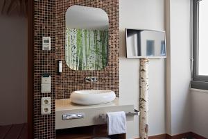 慕尼黑茧史塔克豪斯酒店的一间带水槽和镜子的浴室以及一台电视