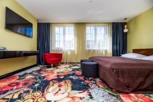 帕兰加Amsterdam Plaza Hotel & SPA的酒店客房,配有一张床和一张红色椅子