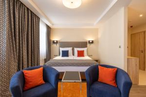布达佩斯Silver Crown Hotel & Residence, Palace Quarter的酒店客房,配有一张床和两把椅子