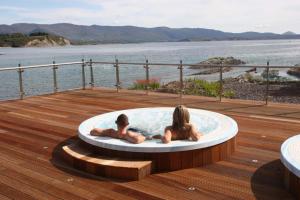 斯尼姆The Woodland Villas at Parknasilla Resort的两人坐在甲板上的热水浴缸中