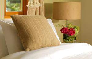 斯尼姆The Woodland Villas at Parknasilla Resort的床上的枕头,上面有玫瑰花瓶