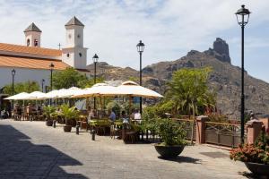 克鲁兹·德·特赫达Casa Maria with Roque Nublo view的山前带桌子和遮阳伞的庭院