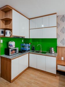 富国Coco Homestay的厨房配有白色橱柜和绿色墙壁