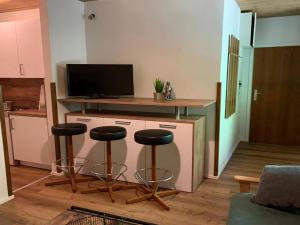 海利根布卢特Apartment Glockner-1 by Interhome的客厅设有2个酒吧凳和1台电视
