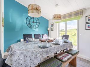 金罗斯Chalet Loch Leven Lodge 16- Robin's Nest by Interhome的一间带桌椅和时钟的用餐室