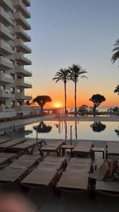 多列毛利诺斯Hotel Ocean House Costa del Sol, Affiliated by Meliá的一个带躺椅和棕榈树的游泳池,并可欣赏日落美景