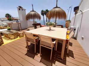 马拉加Suite Deluxe Face Mer Apart Malaga的一个带桌椅的木制甲板和大海